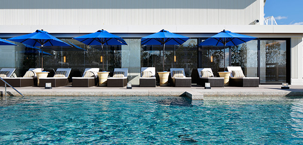 屋外温水プールの青いパラソル風景