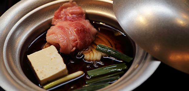 鍋に入れられた肉と豆腐、玉ねぎとネギ